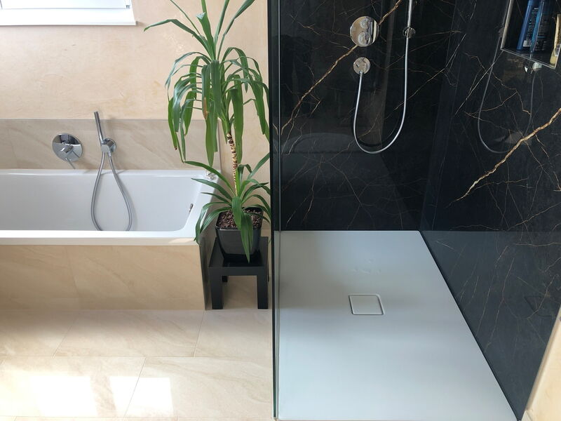 Badezimmer mit weißer Duschwanne, Badewanne und Fliesenboden